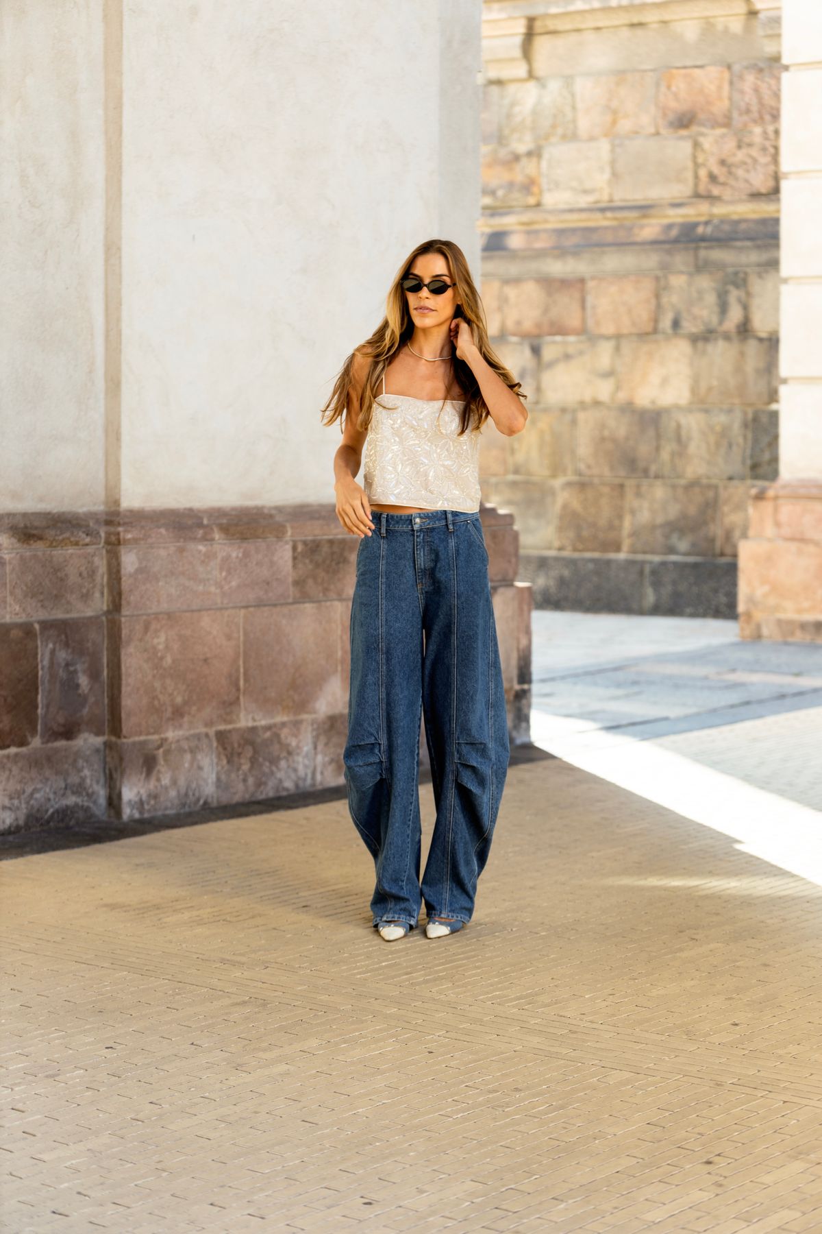 Woman in high-waisted baggy jeans and a fitted crop top with white chunky sneakers
