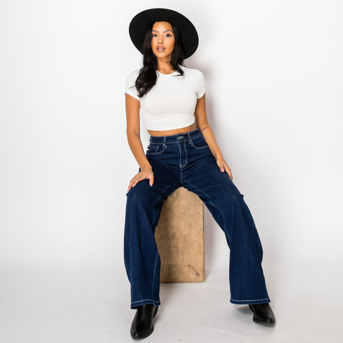 Woman in baggy jeans and a fitted ribbed tank top with layered gold necklaces
