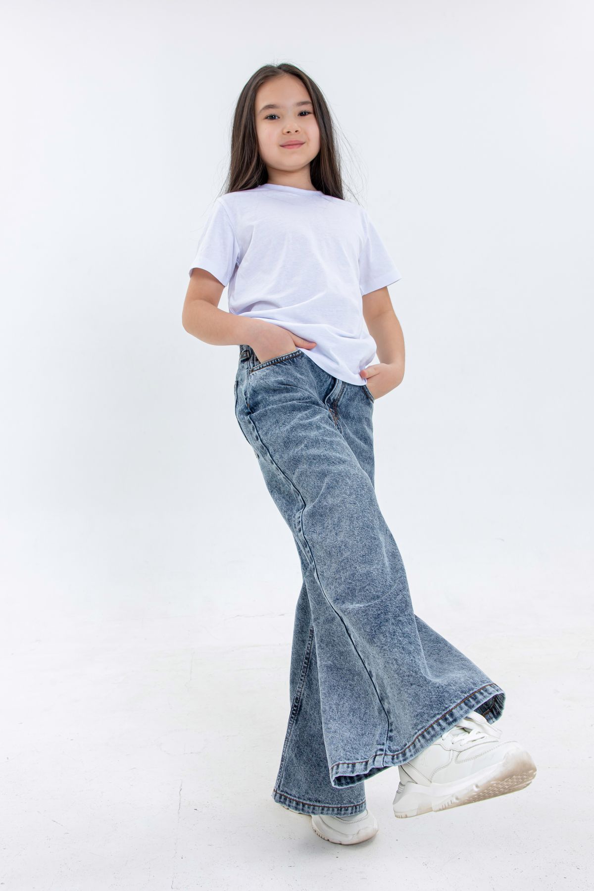 Woman standing on a city street in loose baggy blue jeans and a relaxed top